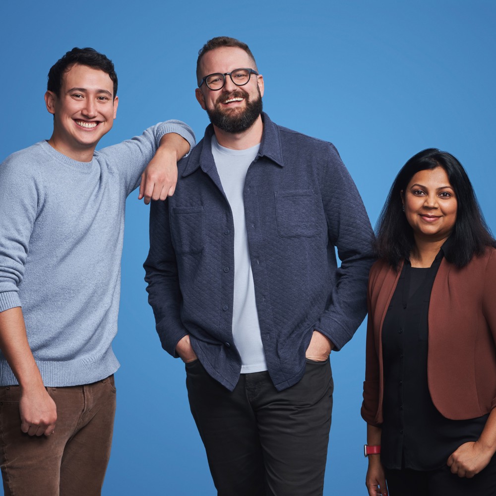 HR employee, mechanical engineer, and analyst in a group photo in front of light blue background