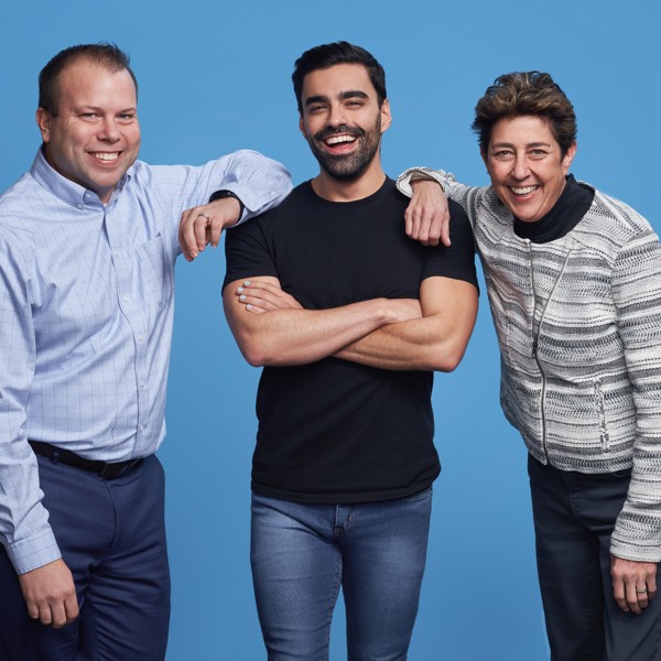 Three employees from HR standing together in front of a light blue background